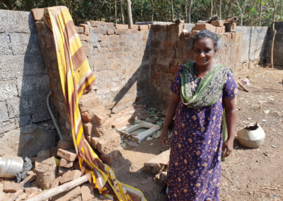 Frau vor einer einfachen Toilette, die mit Unterstützung der Deutsch-Indischen Stiftung gebaut wurde. Sanitäre Einrichtungen schützen die Gesundheit, schenken Privatsphäre und ermöglichen ein Leben in Würde.