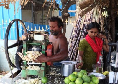 Mann und junge Frau bereiten frischen Zuckerrohrsaft für den Verkauf zu. Die Deutsch-Indische Stiftung unterstützt Menschen dabei, sich durch eigene Arbeit und kleine Einkommensprojekte eine nachhaltige Existenz aufzubauen.