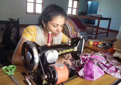 Junge Frau mit körperlicher Behinderung arbeitet an einer Nähmaschine. Die Deutsch-Indische Stiftung unterstützt Menschen mit Behinderungen durch Ausbildung, berufliche Förderung und Hilfe zur Selbstständigkeit.
