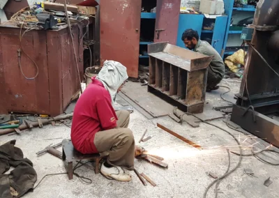 Arbeiter schleift Metall ohne Schutzbrille, Gehörschutz oder Schutzkleidung. Gefährliche Arbeitsbedingungen und fehlender Arbeitsschutz gefährden täglich die Gesundheit vieler Menschen in Indien.